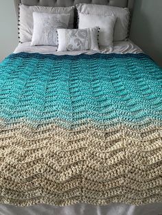 a bed with a blue and white blanket on it's headboard next to pillows