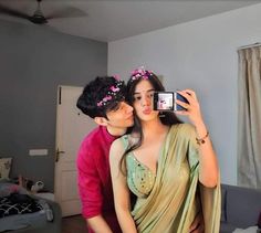 a man taking a picture of a woman in her bedroom while she is wearing a sari