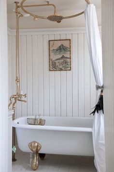 a white bath tub sitting in a bathroom next to a painting on the wall above it