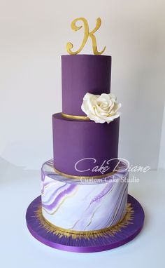 a three tiered cake with purple icing and white flowers