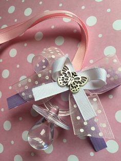 a pink and white polka dot ribbon with a butterfly brooch on it's side