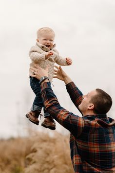 a man holding a baby up in the air