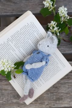 a stuffed animal laying on top of an open book next to some flowers and leaves