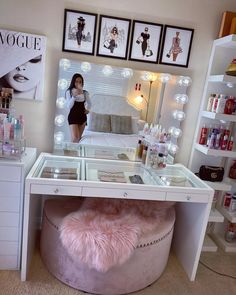 a woman is standing in front of a vanity with lights on and a stool underneath it