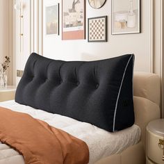 a bed with a black pillow on top of it next to pictures and other items