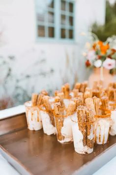 small desserts are arranged on a metal tray in front of a flower pot and window