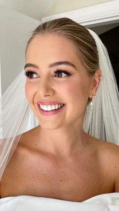 a woman wearing a wedding veil and smiling at the camera with her hair pulled back