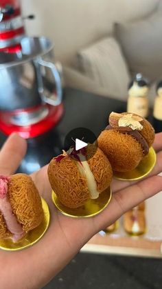 three miniature pastries on small plates in the palm of a person's hand