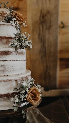 a three tiered cake with white frosting and flowers