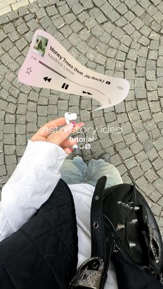 someone is holding up a white toothbrush in front of their feet on a cobblestone street