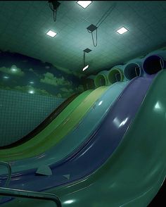 there are many slides in the children's indoor play area that is painted green, blue and purple