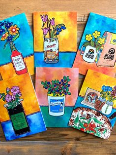 four cards with flowers and vases on them are sitting on a wooden table next to each other