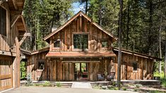 a large wooden building sitting in the middle of a forest next to tall pine trees