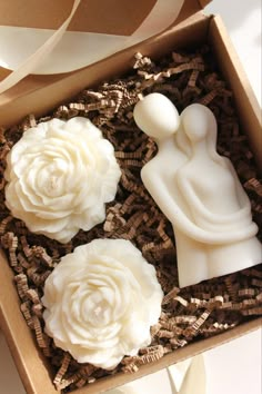 three soaps in a box with white flowers on them and ribbons around the edges