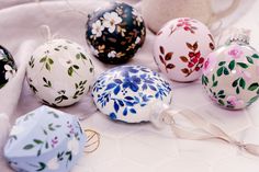 there are many different colored ornaments on the table with white cloth around them and one has a flowered ornament hanging from it