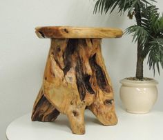 a wooden stool sitting on top of a white table next to a potted plant