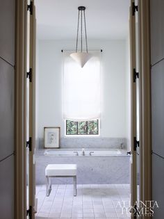 an open door leading to a bathroom with a large tub and white tile flooring