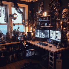 a computer desk topped with two monitors next to a window covered in skulls and chains