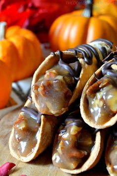 some kind of food that is sitting on a wooden table with pumpkins in the background