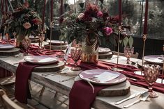 the table is set with plates, silverware and red napkins for an elegant dinner