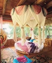 a canopy bed with curtains on top of it in a room filled with furniture and rugs