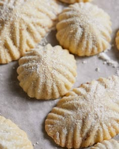 several small pastries covered in powdered sugar sit on a baking sheet, ready to be baked