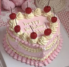 a heart shaped birthday cake with cherries on top