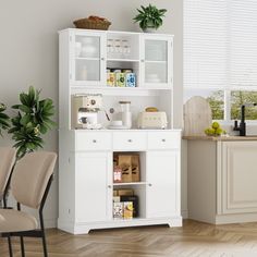 a kitchen with white cabinets and chairs in front of the counter top, next to a potted plant