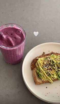 a white plate topped with a piece of toast next to a purple smoothie