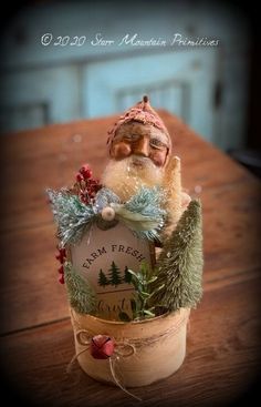 an old fashioned santa clause sitting in a potted planter with pine cones and evergreens