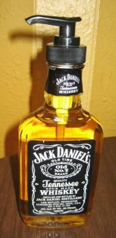 a bottle of jack daniels whiskey sitting on top of a wooden table next to a wall