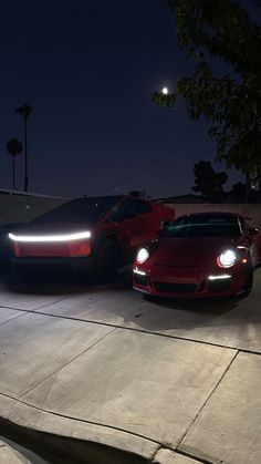 two sports cars parked next to each other at night