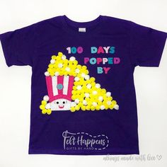 a purple t - shirt with yellow and white candies on it that says 100 days popped by