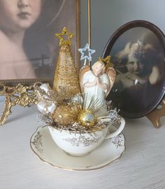 an angel figurine sitting on top of a teacup next to a christmas tree