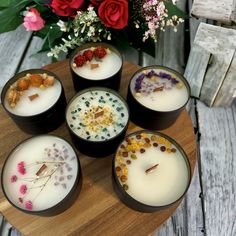 four candles are sitting on a table with flowers in the background