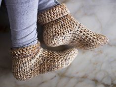 someone wearing knitted slippers standing on a marble floor