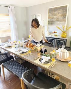 a woman standing in front of a table filled with food and drinks on top of it