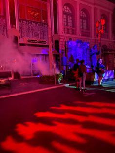 two people standing on the street in front of a building with steam coming out of it