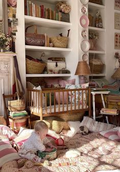 a baby sitting on the floor in front of a crib and bookshelf