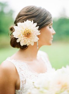 a woman in a wedding dress with a flower in her hair, looking off into the distance