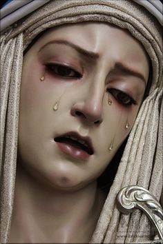 a close up of a statue with tears on her face