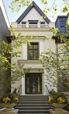 a white house with two large planters in front of it and stairs leading up to the door