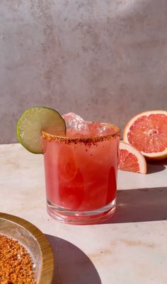 grapefruit margarita with lime and garnish on the rim next to sliced grapefruit