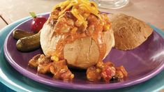 a purple plate topped with a baked potato covered in chili