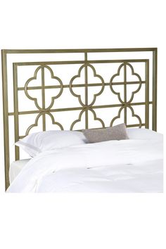 a metal headboard with an intricate design on the top and bottom, along with white bedding