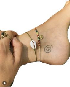 a woman's foot with three different bracelets on her left and one has a shell in the middle