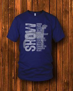 a blue t - shirt with the words show on it, hanging against a wooden wall