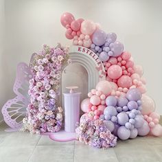 there are balloons and flowers on the floor in front of an arch that says it's birthday