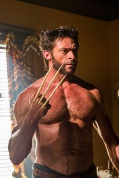 a shirtless man holding two wooden sticks in his hand and looking at the camera