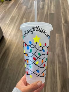 a hand holding a plastic cup decorated with christmas lights and the words merry christmas on it